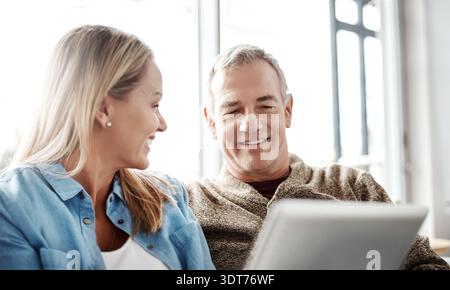 Tablet, sorridi e coppia sul divano per lo streaming, i video e il collegamento nel salotto di casa. Tecnologia, uomo felice e maturo con donna e abbonamento Foto Stock