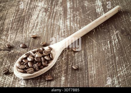 Close-up di un cucchiaio di legno riempita con arrosti di chicchi di caffè Foto Stock