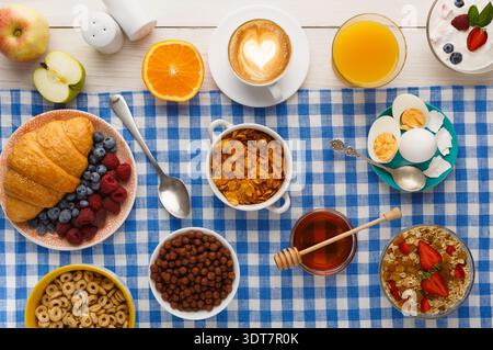 Una varietà di cibi per la colazione è organizzata su un panno a scacchi blu Foto Stock