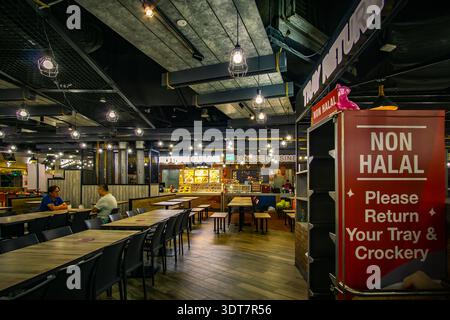 Interno di una moderna area ristoro a IMM Singapore con decor in stile industriale, con una stazione di ritorno con cartello 'non-Halal', Foto Stock