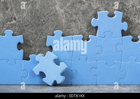 Puzzle senza finitura blu su sfondo grigio cemento. Concetto aziendale di team Foto Stock