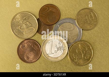 Monete miste in euro di vari valori su una superficie di metallo dorato Foto Stock