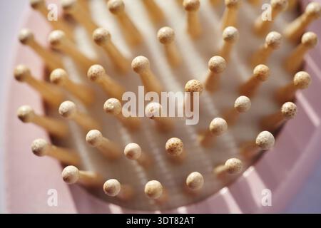 Vista dall'alto macro di spille in legno che creano un motivo ritmico. Sfondo astratto delle setole dello strumento per la cura dei capelli di bambù alla luce del sole. Eco-fr naturale Foto Stock