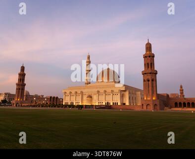 Grande Moschea del Sultano Qaboos a Mascate, Oman. Iconica architettura islamica con cupole dorate e minareti torreggianti. Tranquillo paesaggio con prati verdi a. Foto Stock
