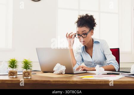 La donna lavora su un notebook in ufficio e controlla le informazioni mentre è seduta alla scrivania Foto Stock