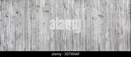 Parete grigia in calcestruzzo che mostra una trama di legno a grana resistente agli agenti atmosferici che forma uno sfondo industriale Foto Stock