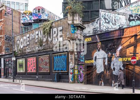 Graffiti Street art sulla Great Eastern Street, Shoreditch, inclusi due vecchi treni sotterranei sopra la strada. Adoriamo e resistiamo a vicenda Foto Stock