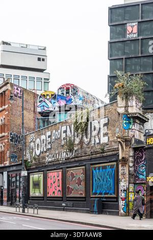 Graffiti Street art sulla Great Eastern Street, Shoreditch, inclusi due vecchi treni sotterranei sopra la strada. Adoriamo e resistiamo a vicenda Foto Stock