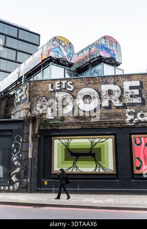 Graffiti Street art sulla Great Eastern Street, Shoreditch, inclusi due vecchi treni sotterranei sopra la strada Foto Stock