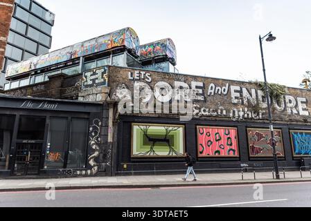 Graffiti Street art sulla Great Eastern Street, Shoreditch, inclusi due vecchi treni sotterranei sopra la strada. Adoriamo e resistiamo a vicenda Foto Stock