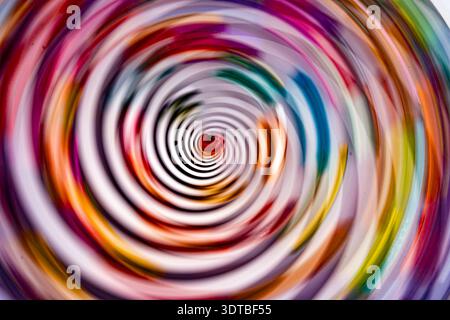 fotografia astratta caratterizzata da un vivace e vorticoso motivo di cerchi concentrici con un mix di colori vivaci, tra cui rosso, rosa, blu, verde e a te Foto Stock