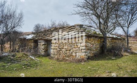 Vecchia capanna di montagna abbandonata e in rovina costruita solo con rocce, edificio in stile tradizionale nella storia serba Foto Stock