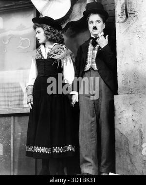 Charlie Chaplin interpreta il barbiere ebreo, tenendosi per mano con Paulette Goddard nel ruolo di Hannah, in una pubblicità ancora tratta dal film del 1940 "il grande dittatore". Entrambi gli attori sono in costume, con Chaplin che indossa il suo iconico cappello da bowler e baffi, e Goddard vestito con un abbigliamento tradizionale con uno scialle a motivi geometrici. Foto Stock