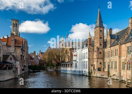 Bruges, Belgio - 14 febbraio 2026: Vista iconica di Rozenhoedkaai con case medievali in mattoni e torre di Belfry lungo il canale nel centro storico Foto Stock