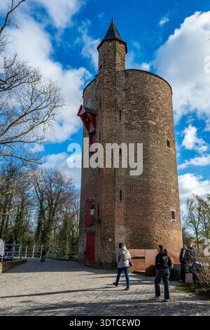 Bruges, Belgio - 14 febbraio 2026: Visitatori nei pressi del Poertoren, noto anche come la Torre delle polveri, una torre difensiva medievale in mattoni del 1397 a Bruges. Foto Stock