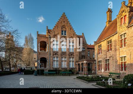 Bruges, Belgio - 14 febbraio 2026: Edifici storici in mattoni di Sint-Janshospitaal illuminati dalla calda luce serale nel centro medievale della città. Foto Stock