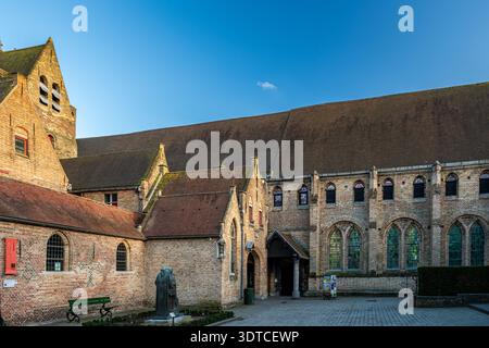 Bruges, Belgio - 14 febbraio 2026: Edifici storici in mattoni di Sint-Janshospitaal con scultura contemporanea nel cortile dell'ex medieva Foto Stock