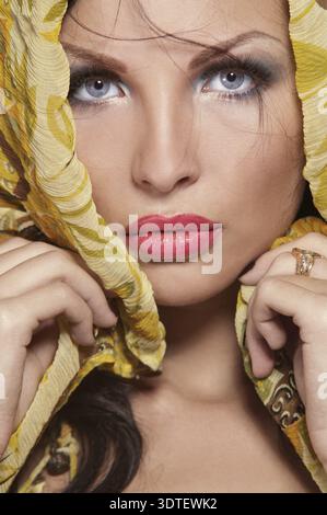 Ritratto di una giovane bella bruna che tiene un pezzo di stoffa arancione Foto Stock