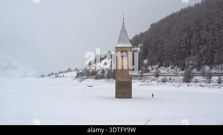 Campanile sommerso di Curon Venosta nel lago ghiacciato di Resia. La famosa torre della chiesa sommersa del XIV secolo di Old Curon. Foto Stock