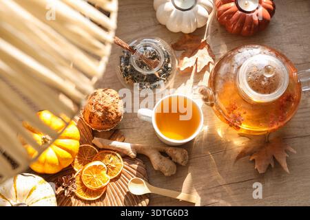 Teiera con rowan, tazza di tè verde vicino al muffin e zenzero sul tavolo in camera. Primo piano Foto Stock