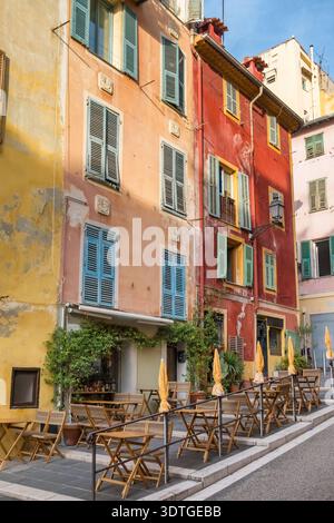 Street Cafe con tavoli in legno ed edifici colorati nella città vecchia di Nizza Foto Stock