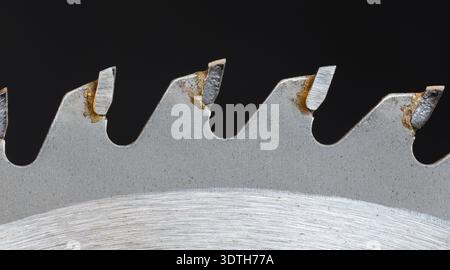 Primo piano dei denti della sega circolare con punta in carburo su sfondo nero Foto Stock