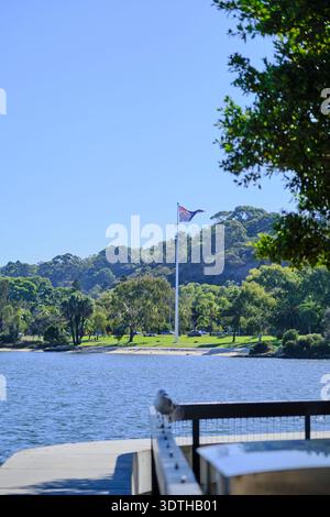 Un tranquillo scatto verticale che cattura la bandiera australiana sventolando con orgoglio contro un cielo azzurro. Foto Stock