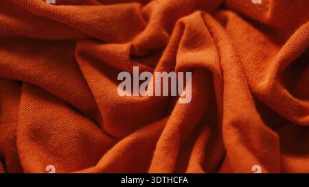 Un tessuto di cotone arancione consumato con puntine visibili sulla superficie ruvida. Primo piano. Foto Stock