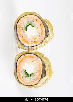 Bicchierino di due involtini di sushi tempura fritti con formaggio cremoso al salmone. Stuzzicanti piatti giapponesi su uno sfondo bianco minimalista. Luce pulita e dai toni alti Foto Stock