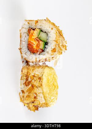 Primo piano di due sushi roll giapponesi su uno sfondo bianco pulito. Un rotolo presenta una sezione trasversale con cetriolo di salmone, ricoperto da scaglie di bonito. Il Foto Stock