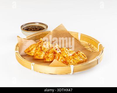 Appetitoso cibo asiatico. Gnocchi fritti dorati croccanti serviti in una vaporiera di bambù con salsa di soia scura. Composizione minimalista con luminoso, cle Foto Stock