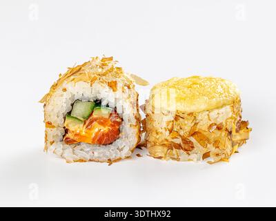Primo piano di due sushi roll giapponesi su uno sfondo bianco pulito. Un rotolo presenta una sezione trasversale con cetriolo di salmone, ricoperto da scaglie di bonito. Il Foto Stock