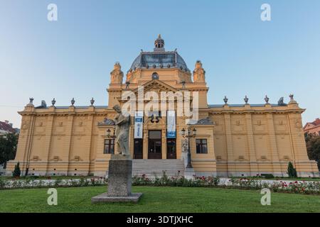ZAGABRIA, CROAZIA, 08.10.2018: Grand Art Pavilion a Zagabria con architettura classica, statue in pietra, giardino paesaggistico e facciata ornata al tramonto. Storico Foto Stock