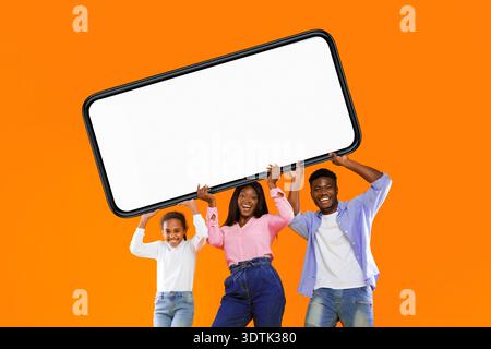 Gruppo di persone con un grande telefono vuoto davanti allo sfondo arancione Foto Stock