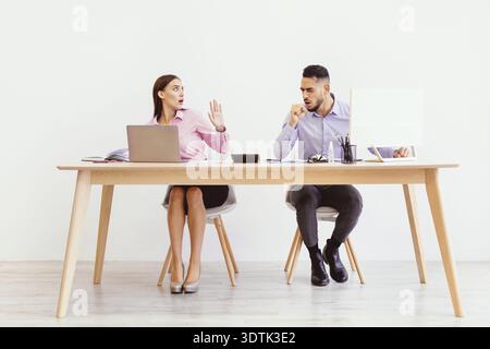 I colleghi parlano durante una riunione in un semplice spazio ufficio con un design pulito Foto Stock