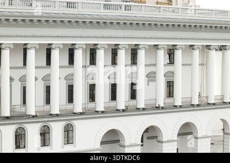 Un grande edificio bianco presenta architettura classica con prominenti colonne ioniche e finestre ad arco ripetute su più livelli Foto Stock