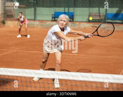 Giovane donna che gioca a tennis con una donna più anziana Foto Stock