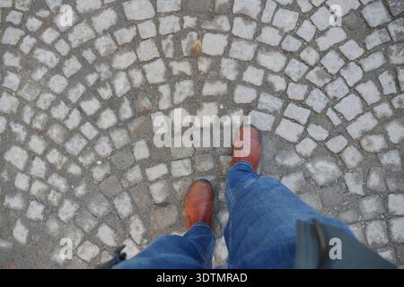 Guardando le scarpe in fondo alla strada acciottolata Foto Stock