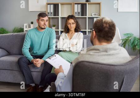 Marito e moglie visita medico con clipboard per consultazione su diagnosi in ufficio ospedaliero Foto Stock