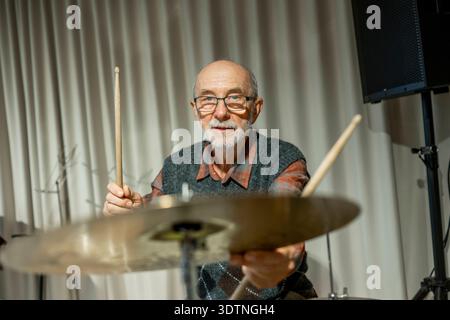Uomo anziano che si diverte a suonare la batteria. Uomo anziano che si diverte a suonare la batteria. Musicista in pensione. modello rilasciato Foto Stock