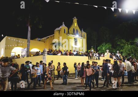 Merida, Messico - 31 ottobre 2018: Visitatori al festival per giorno dei morti seduti e camminando alla chiesa coloniale 'Santa Isabel' di notte Foto Stock