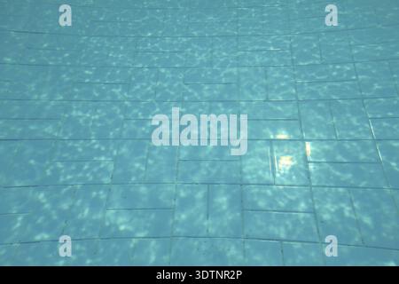 Fondo piscina, sole splendente su piastrelle blu, linee distorte dalla rifrazione dell'acqua, Lapta, Cipro Foto Stock