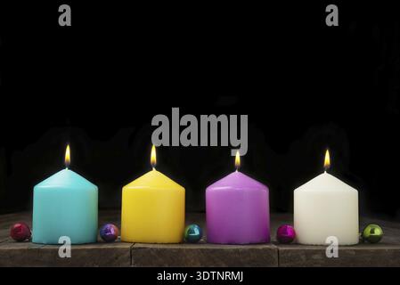Candele multicolore con palline decorative su sfondo nero. Concetto di Capodanno e Natale Foto Stock