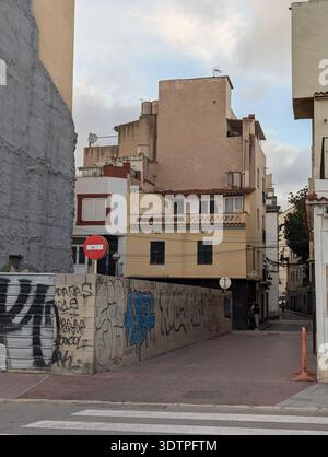 Llored de Mar Spagna 15 settembre 2024 stretto vicolo vuoto tra edifici in età avanzata, muro coperto di graffiti e facciate color pastello sbiadite, cartello segnaletico Q Foto Stock