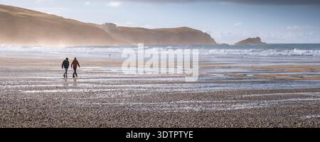 Un'immagine panoramica di due uomini maschi che camminano sulla spiaggia di Fistral a Newquay in Cornovaglia nel Regno Unito. Foto Stock