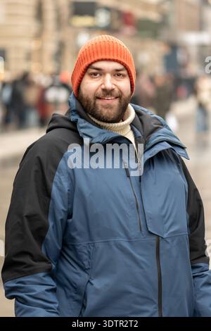Persona adulta con abiti caldi contro i pedoni della città Foto Stock