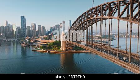 Australia, Sydney: Il Sydney Harbour Bridge e il moderno skyline della città sotto la luce del sole del mattino, l'architettura delle infrastrutture urbane e il traffico dei trasporti su strada. Volo aereo con droni Foto Stock