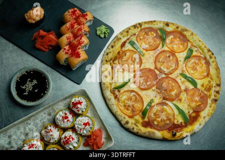 Un'esposizione culinaria unica che propone Pizza con pomodori freschi e peperoni e varie creazioni di sushi su un'elegante superficie di servizio Foto Stock