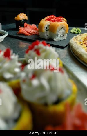 Un assortimento di coloratissimi Sushi Rolls e delicatezze disposte ad arte su un piatto, che mostrano i vivaci sapori e le texture della cucina giapponese Foto Stock