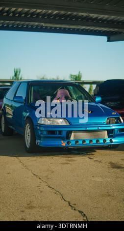 Una splendida auto Blue Modified che presenta caratteristiche personalizzate sotto un riparo in metallo in una giornata serena Foto Stock